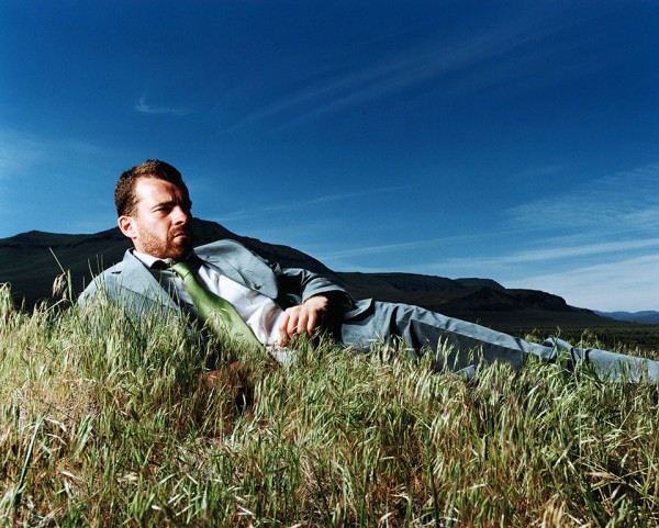 "Businessman lying on grass, Steens Mountains, Oregon, USA," by Matthias Clamer