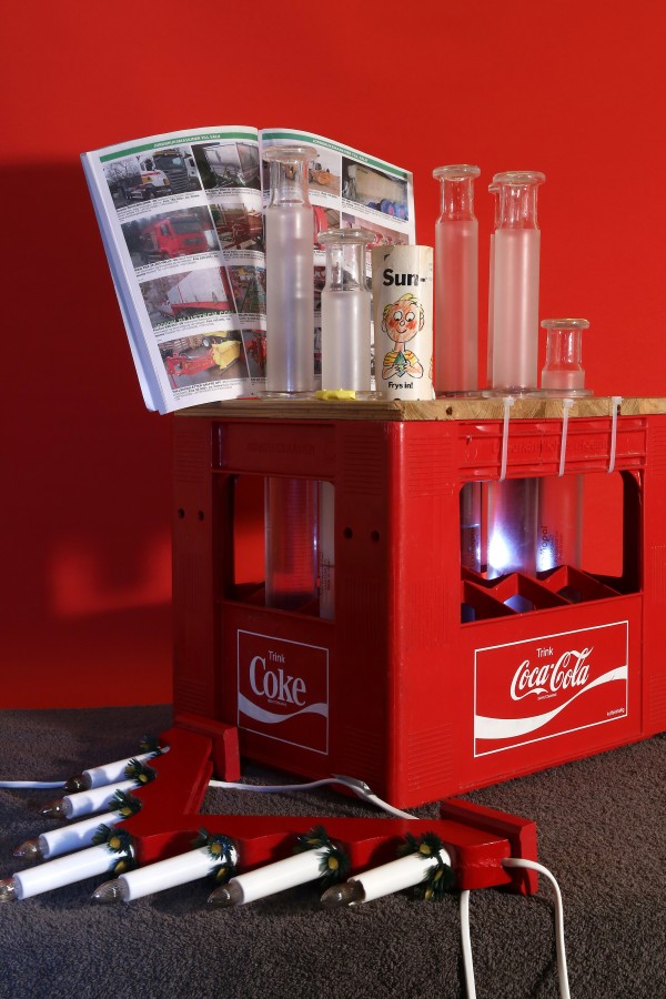 Agricultural machinery classifieds, christmas candlestick, comic magazine and glass syringes in custom made coke crate on towel and tablecloth, Josef Bull, 2014
