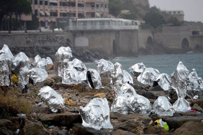 Refugees take shelter on Rocky Italian seafront after being turned away from France.  Published on June 14, 2015 on The Independent. Getty/AFP.