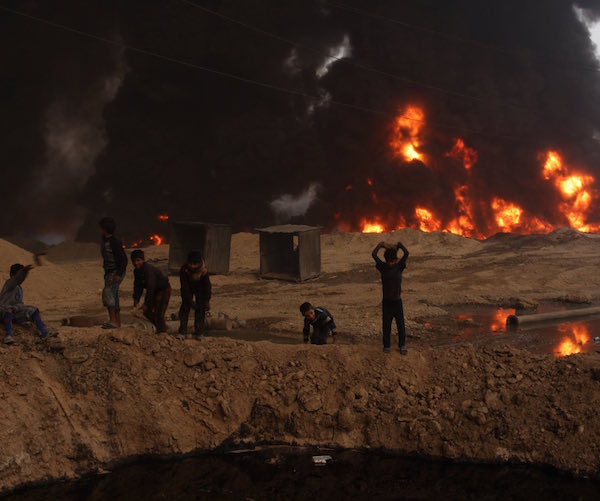 Iraqi children younger than the war tossing rocks into a pool of crude oil. 